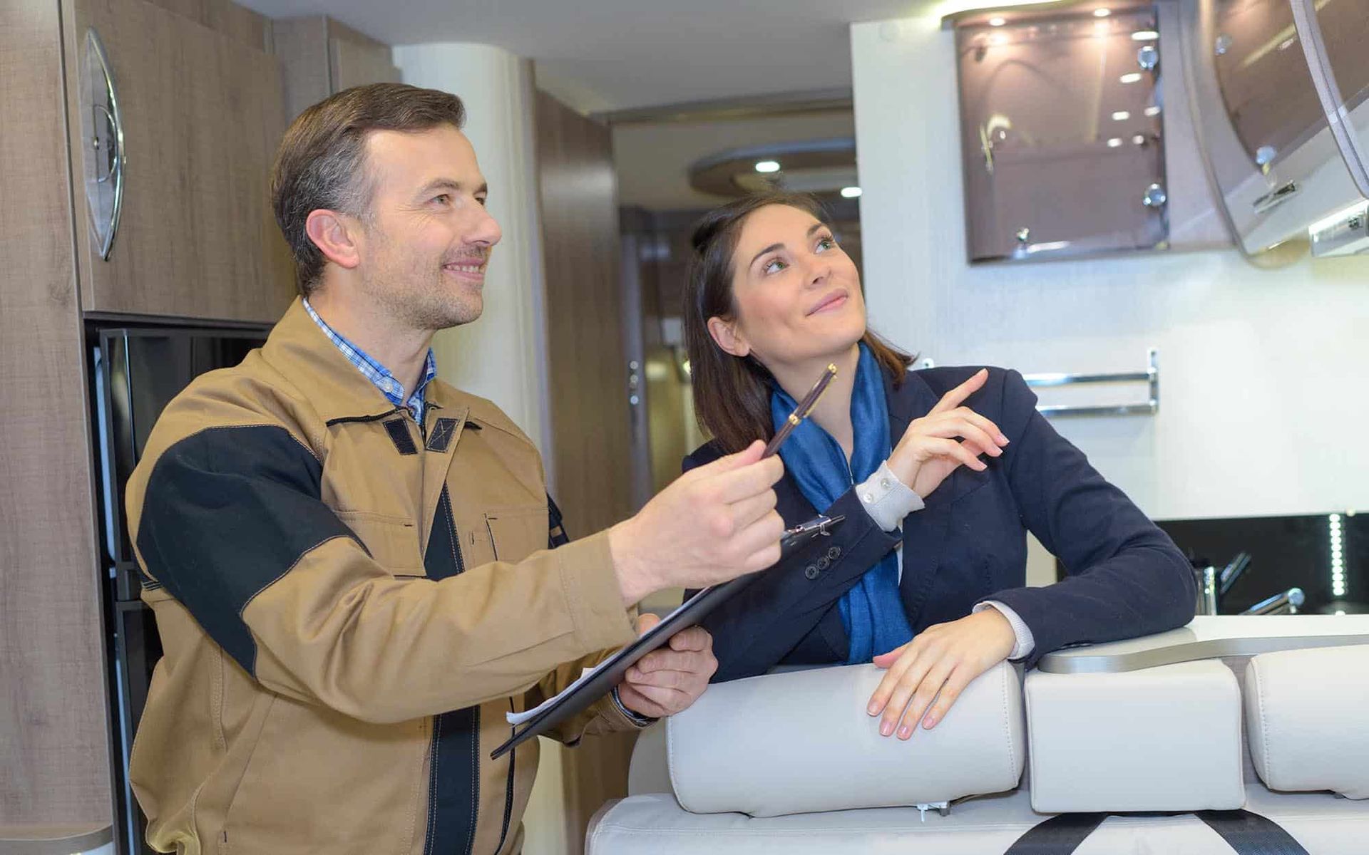 A man and a woman are looking at a camper in a kitchen.