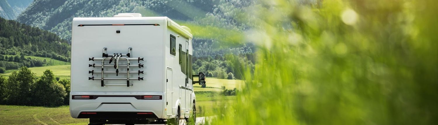 A rv is driving down a road in the mountains.