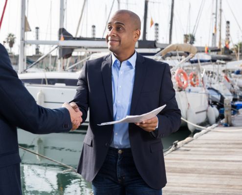 A man in a suit is shaking hands with another man while holding a piece of paper.