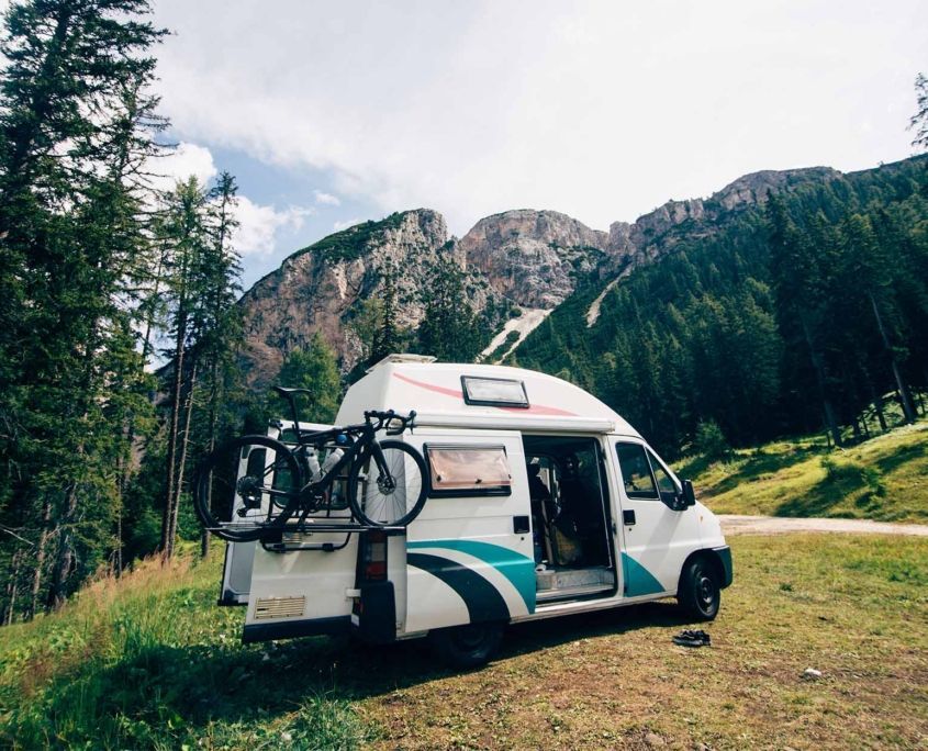 Cute vintage camper van or camping RV parked in wild camping spot in mountain forest