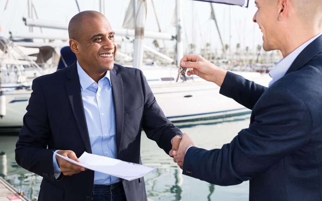 A man in a suit is shaking hands with another man while holding a piece of paper.