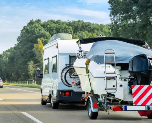 Image of an RV pulling a boat on the highway.