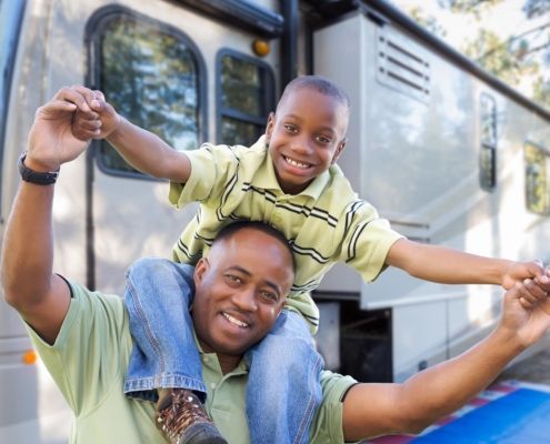 Child on dads shoulders infront of RV