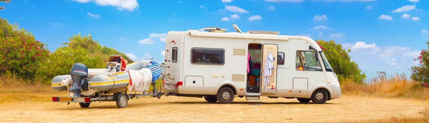 A rv is towing a boat on a trailer.