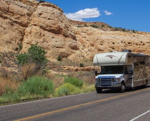 Side view of an RV driving down a desert road