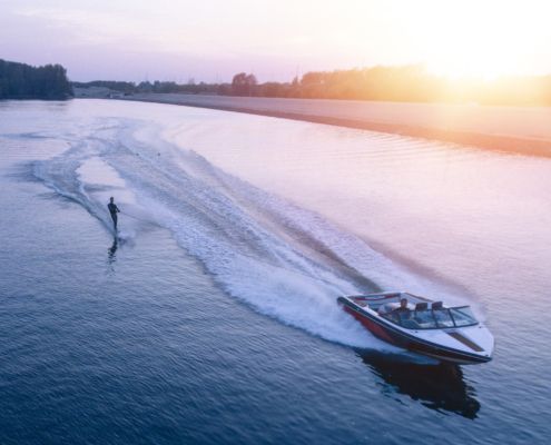 An aerial view of a boat going down a river at sunset.