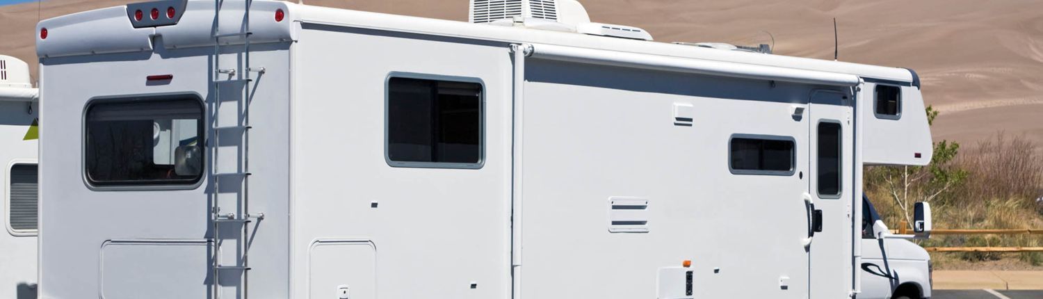 A white rv is parked on the side of the road.