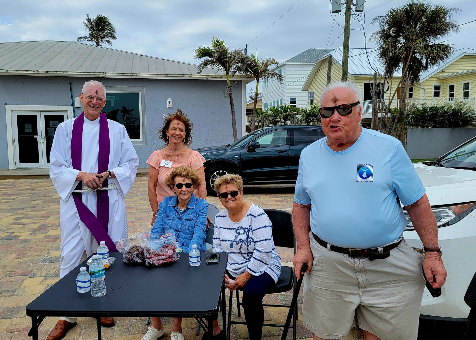 Group of people outside a building, including a priest with ashes on foreheads.