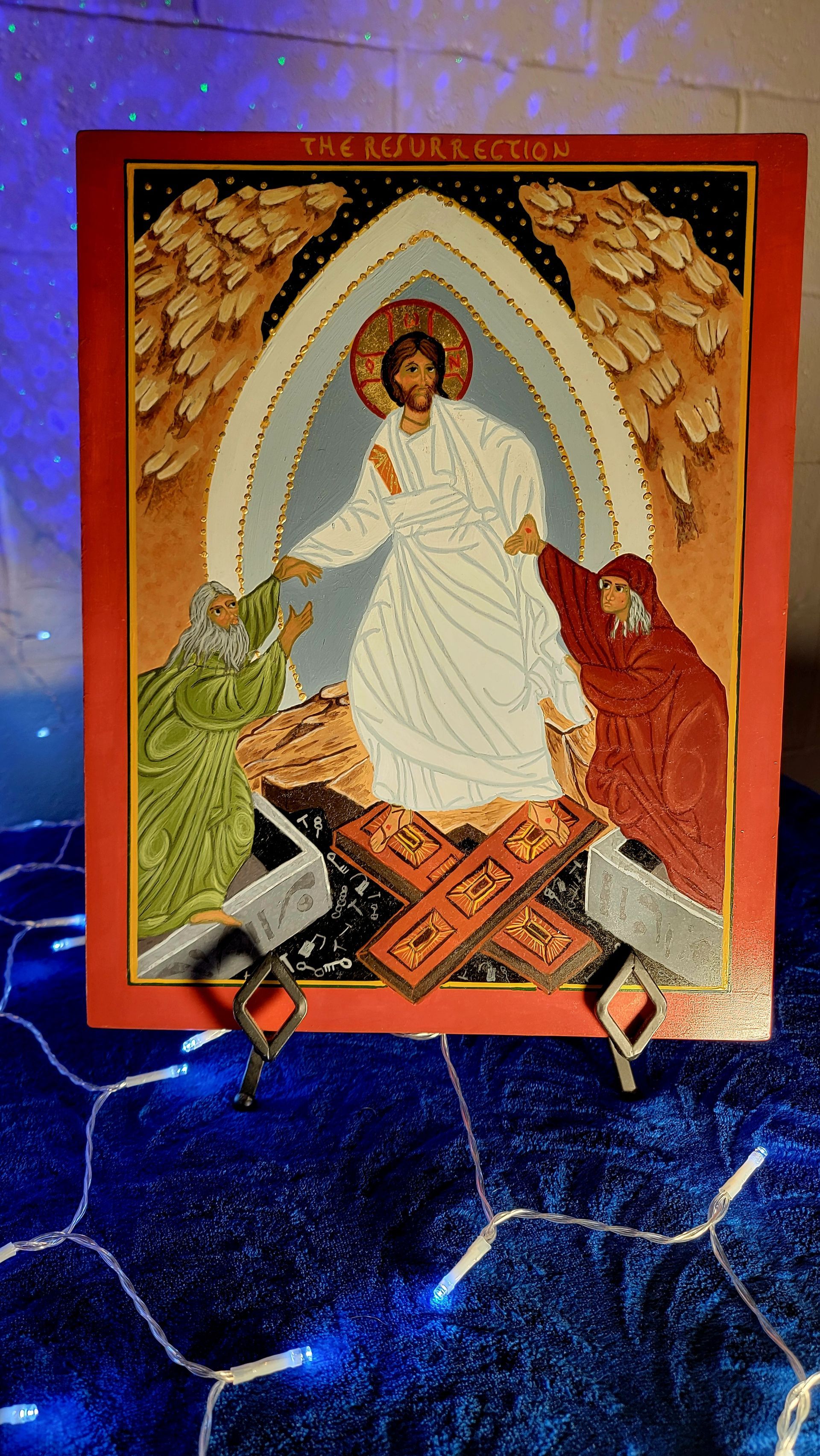 Jesus, in white robe, rises from tomb, reaching to figures in green and red. Ornate gold background.