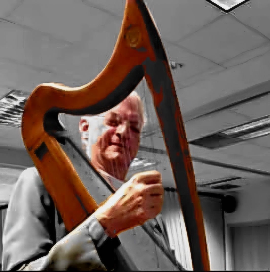 Man playing a wooden harp. Black and white background, the harp is in color.