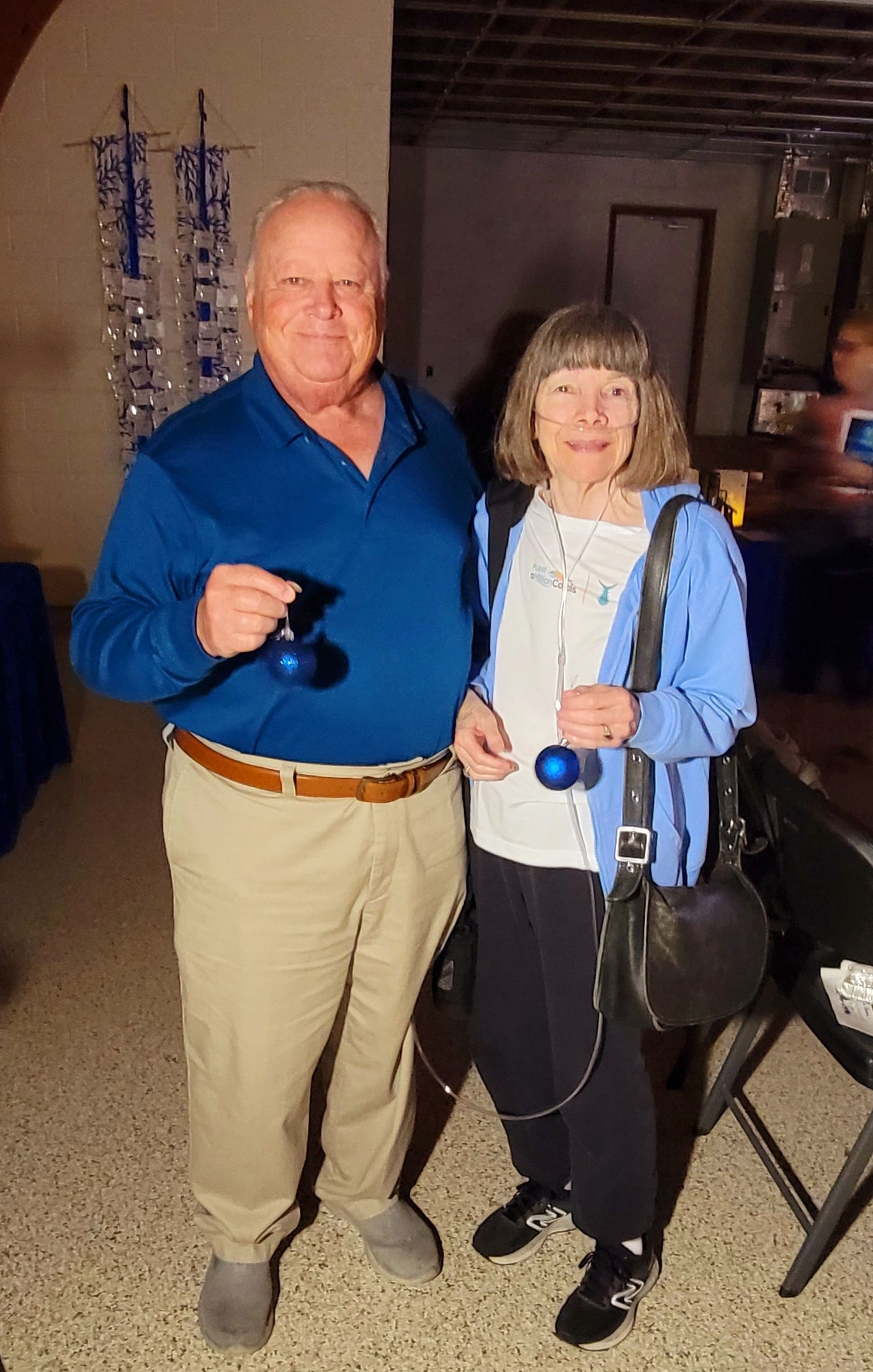 Man and woman holding blue yo-yos. Man wears blue shirt and khaki pants. Woman wears light blue jacket and black pants.