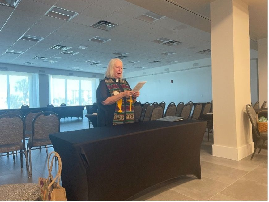 A woman is standing at a table reading a book.