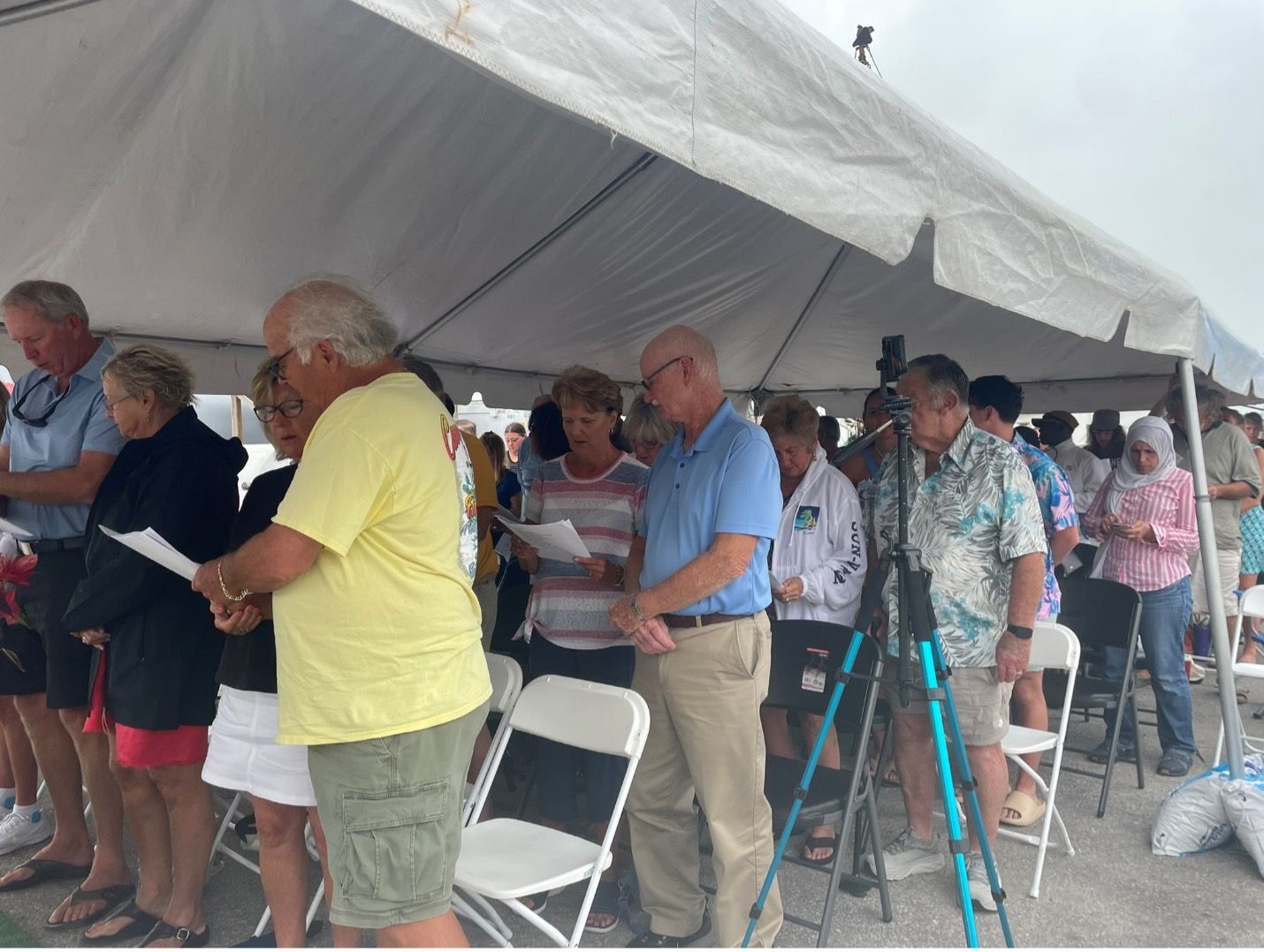 A group of people standing under a tent on the beach