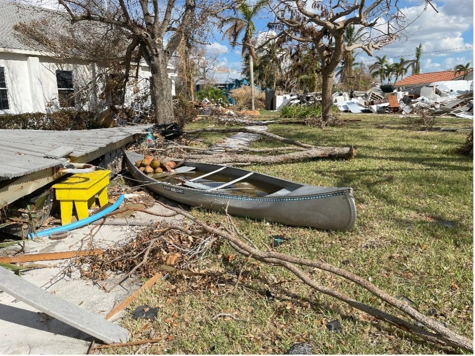 A canoe is sitting in the grass in front of a house.