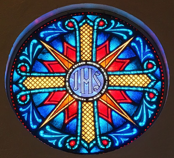 Stained glass window with a cross and the letters 