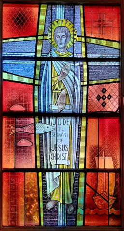 Stained-glass window of a figure with a halo holding a scroll. Blue and red hues. Text: “I am the Resurrection…”