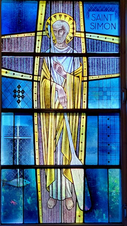 Stained glass window of Saint Simon in yellow and blue, holding an oar.