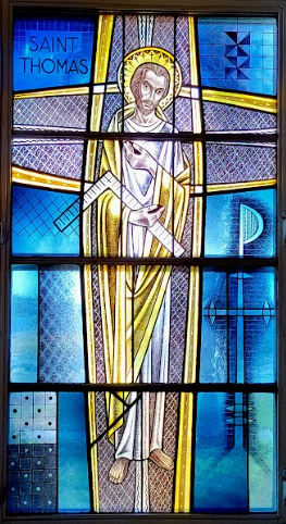 Stained-glass window of Saint Thomas, in white robes, with a cross and a carpenter's square.