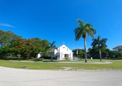 A small white church with palm trees in front of it