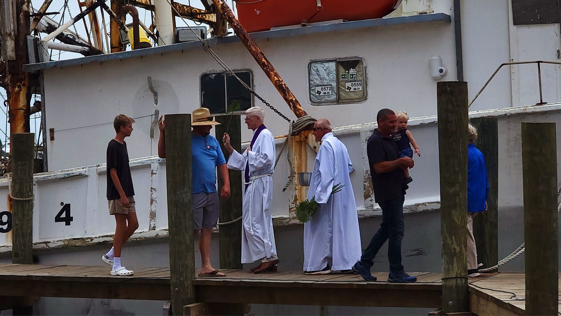 A group of people standing on a dock near a boat with the number 4 on it