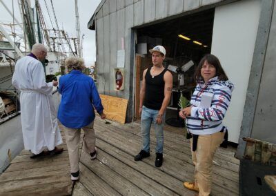 A group of people are standing on a wooden deck in front of a building.