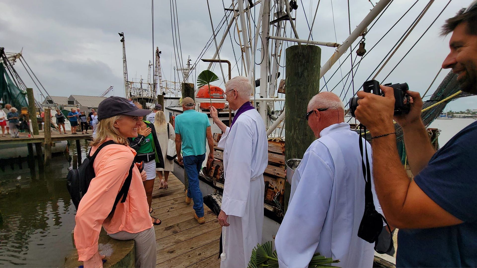 A man is taking a picture of a group of people standing on a dock.