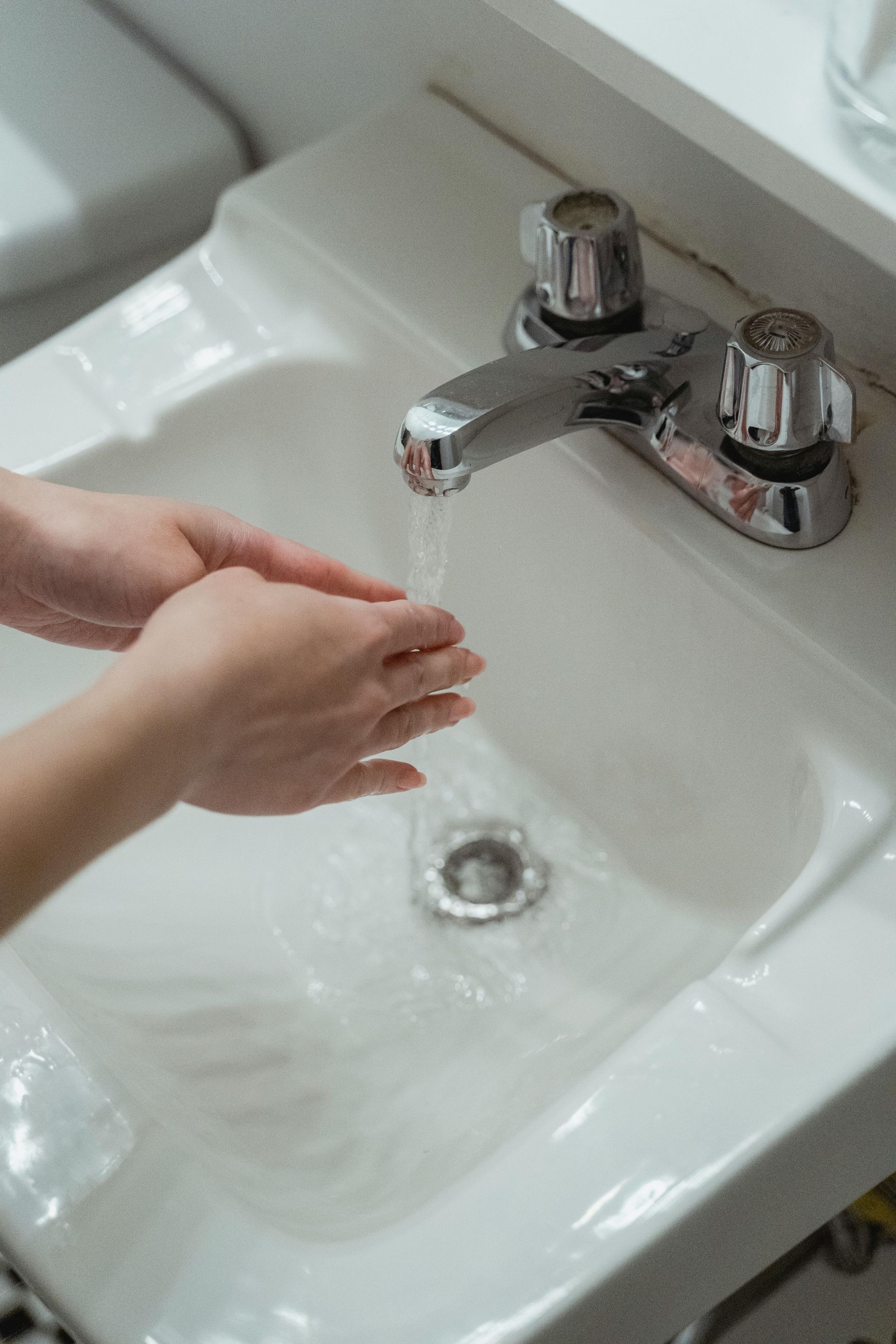 A person is washing their hands in a bathroom sink.