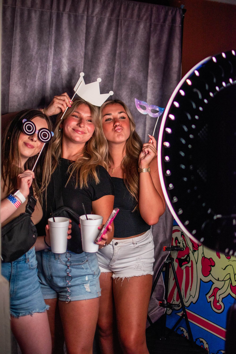 Three young women are posing for a picture in a photo booth.