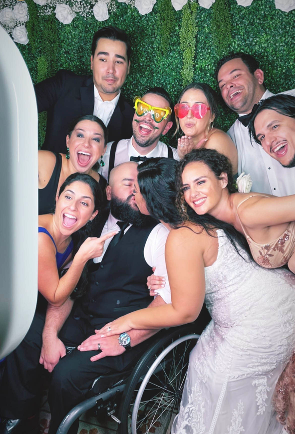 A group of people posing for a picture with a man in a wheelchair.