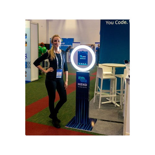 A woman is standing in front of a photo booth that says you code
