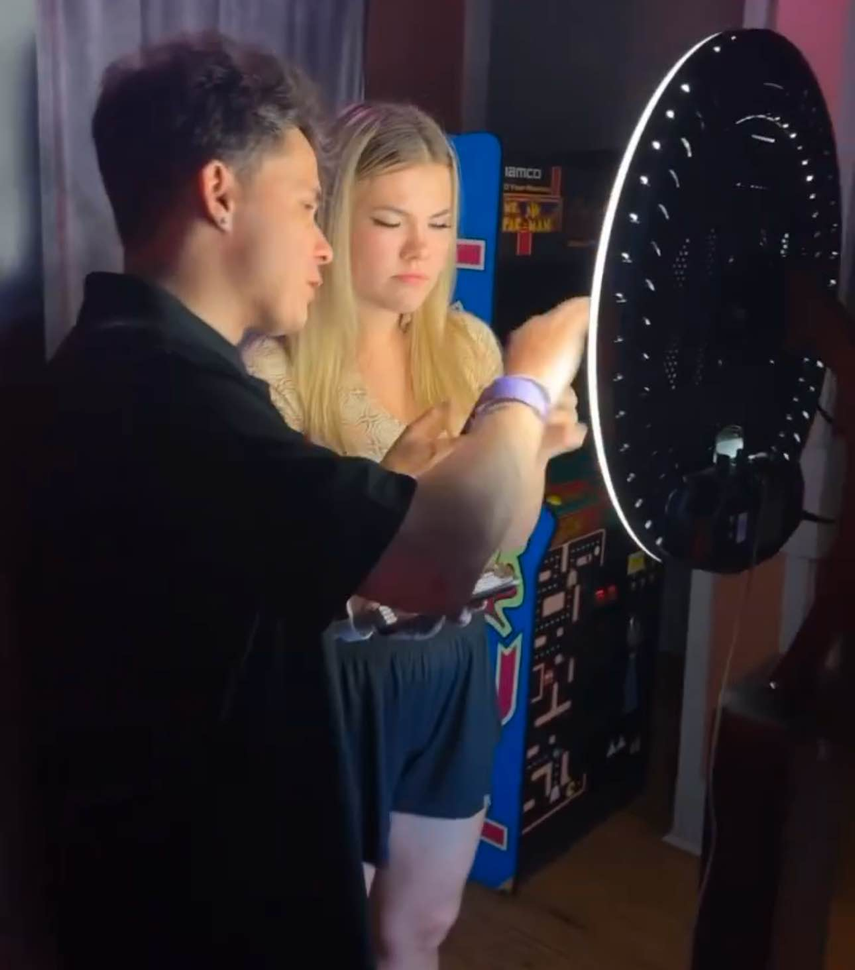 A man and a woman are standing in front of an arcade machine