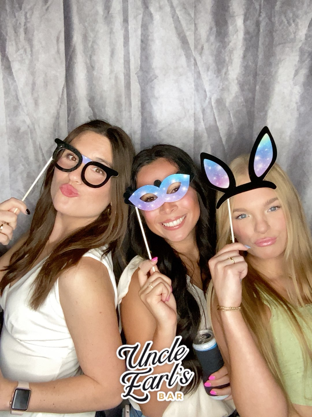 Three women are posing for a picture in a photo booth.
