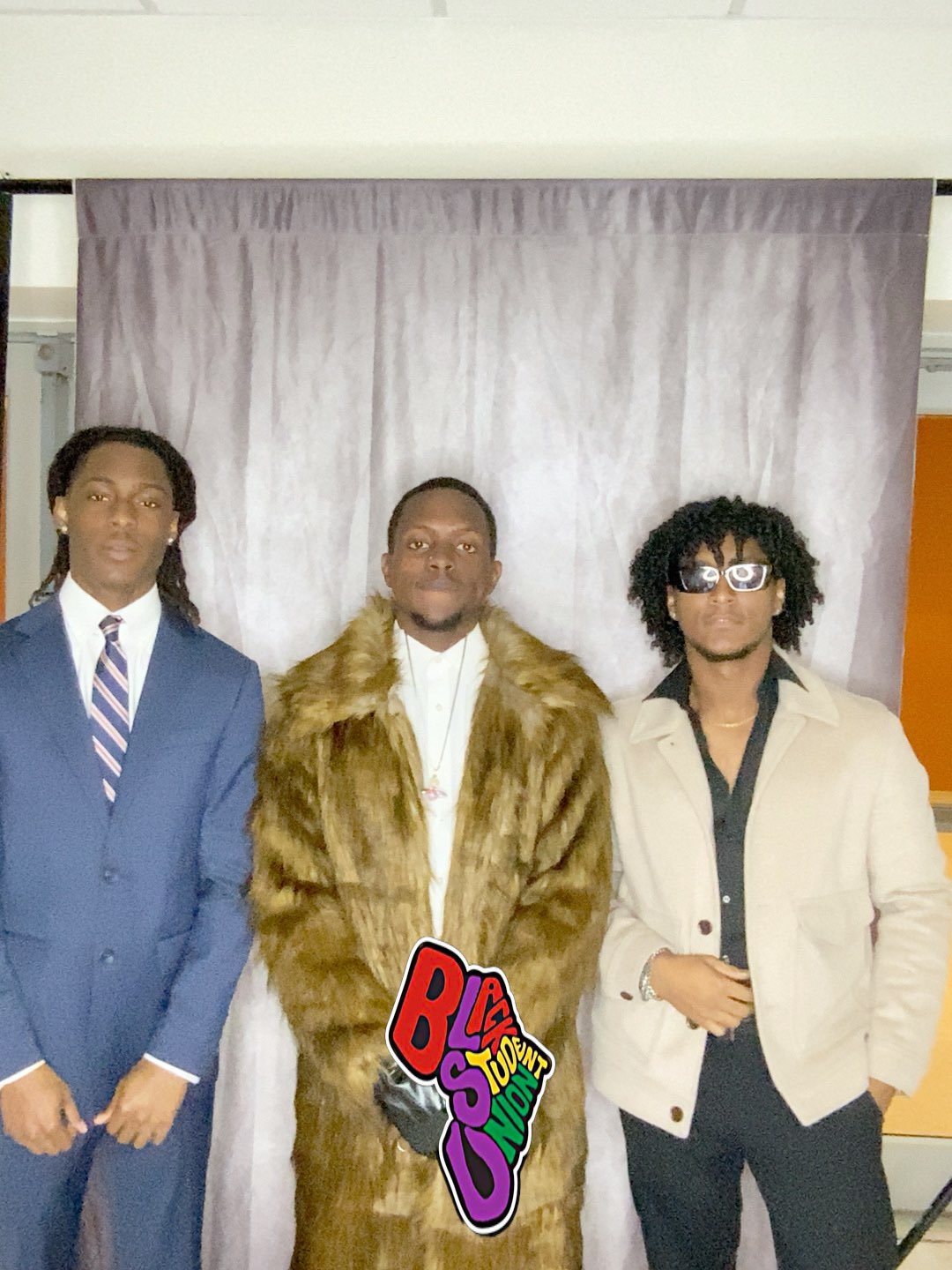 Three men in suits and fur coats are posing for a picture.