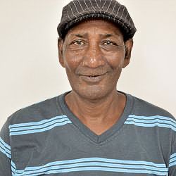 A man wearing a hat and a striped shirt is smiling for the camera.