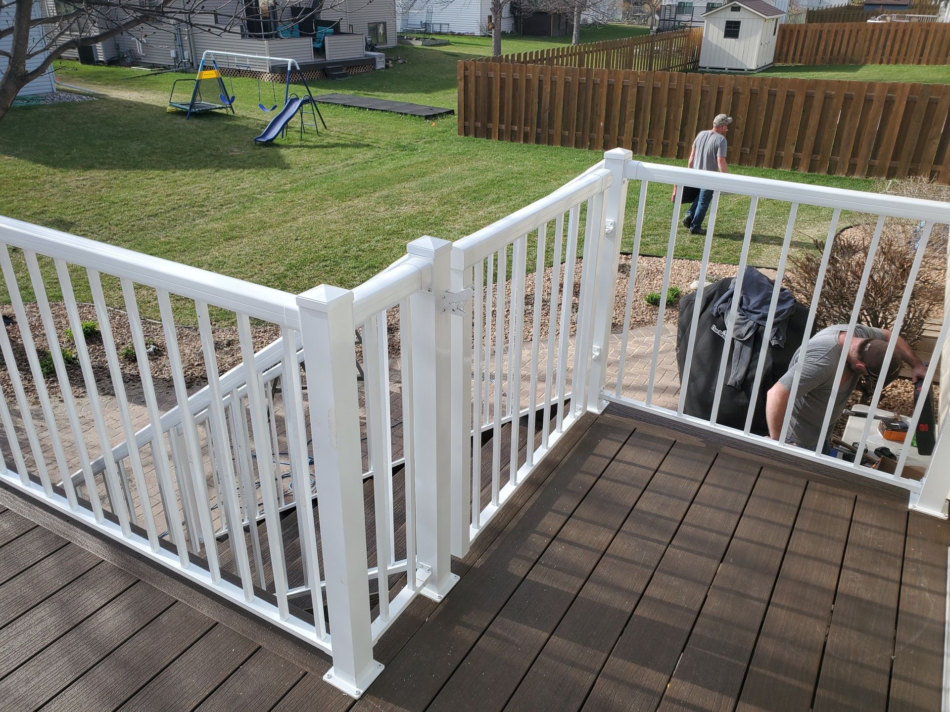 A man is working on a deck with a white railing.