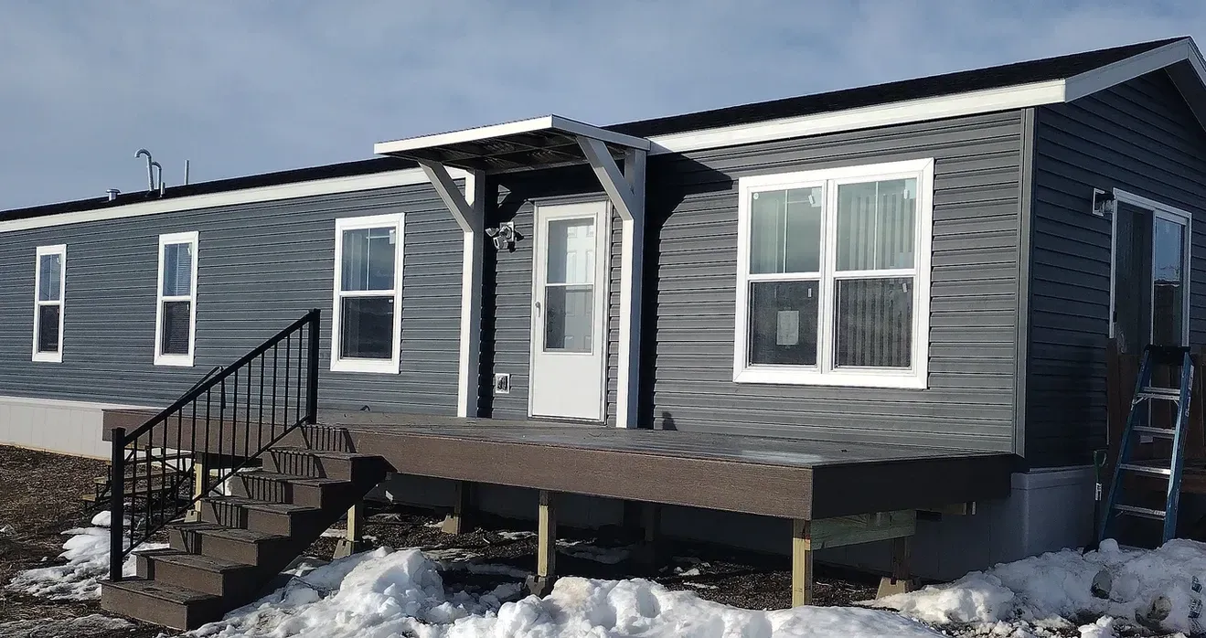 A mobile home with stairs and a porch in the snow.