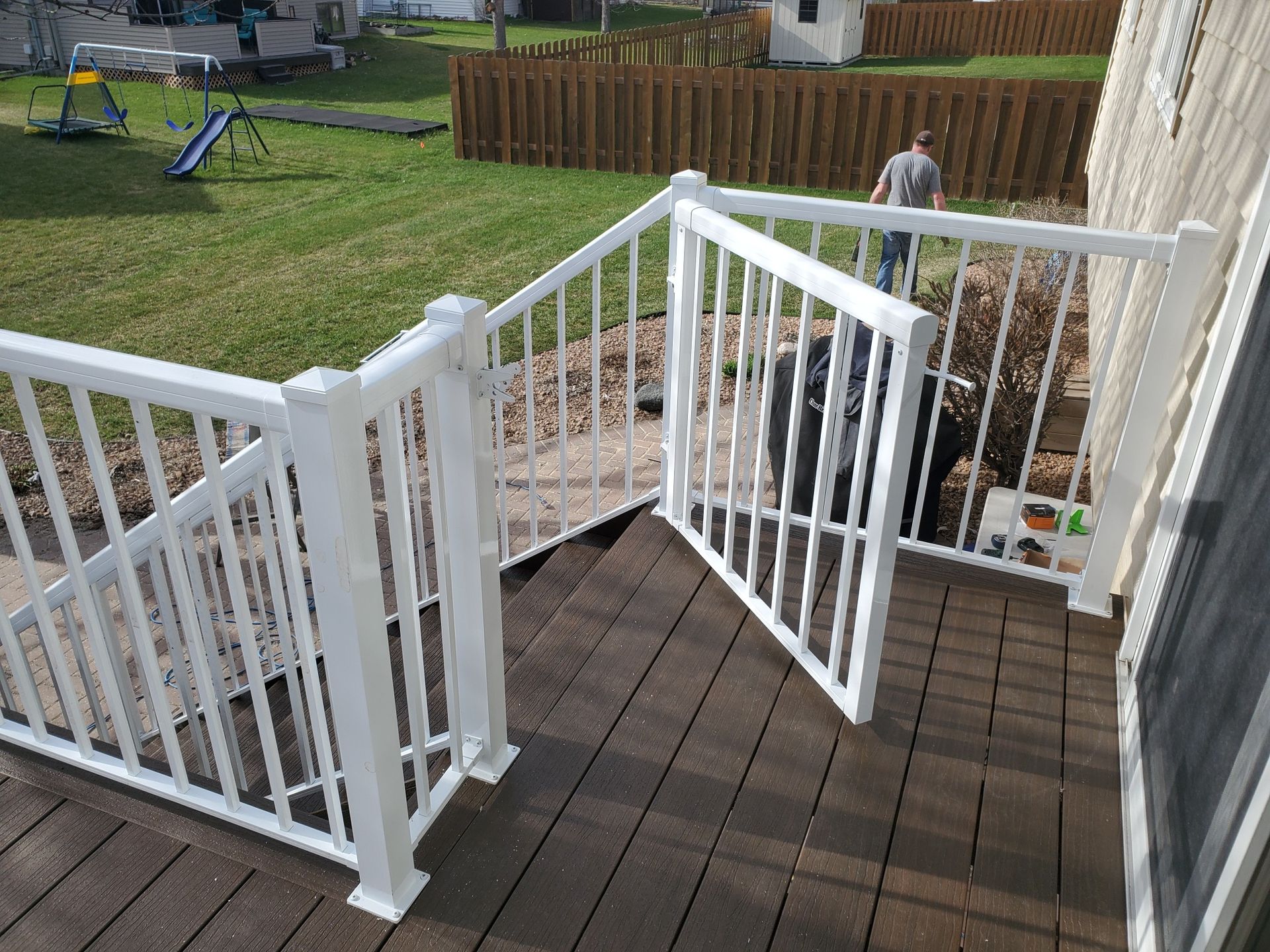A man is standing on a deck with a white railing.