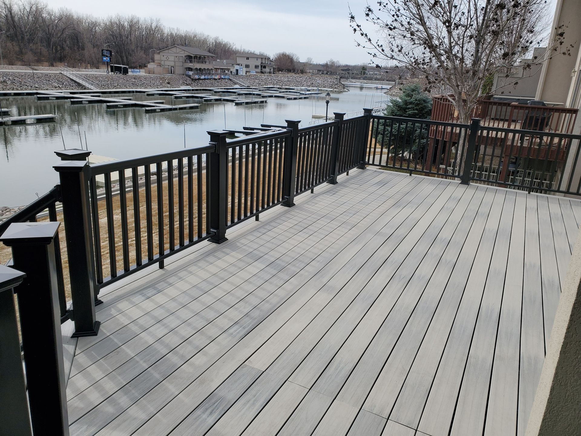 A large deck with a black railing overlooking a body of water.