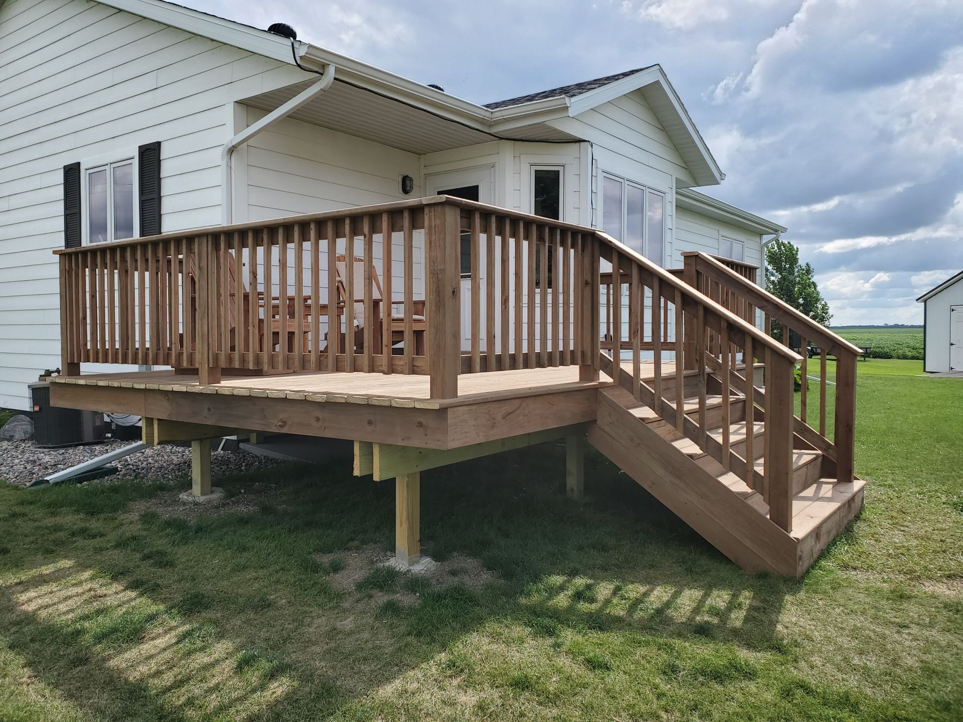 A white house with a wooden deck and stairs