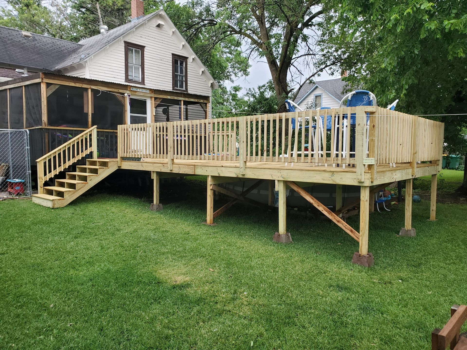 A large wooden deck with stairs is in the backyard of a house.