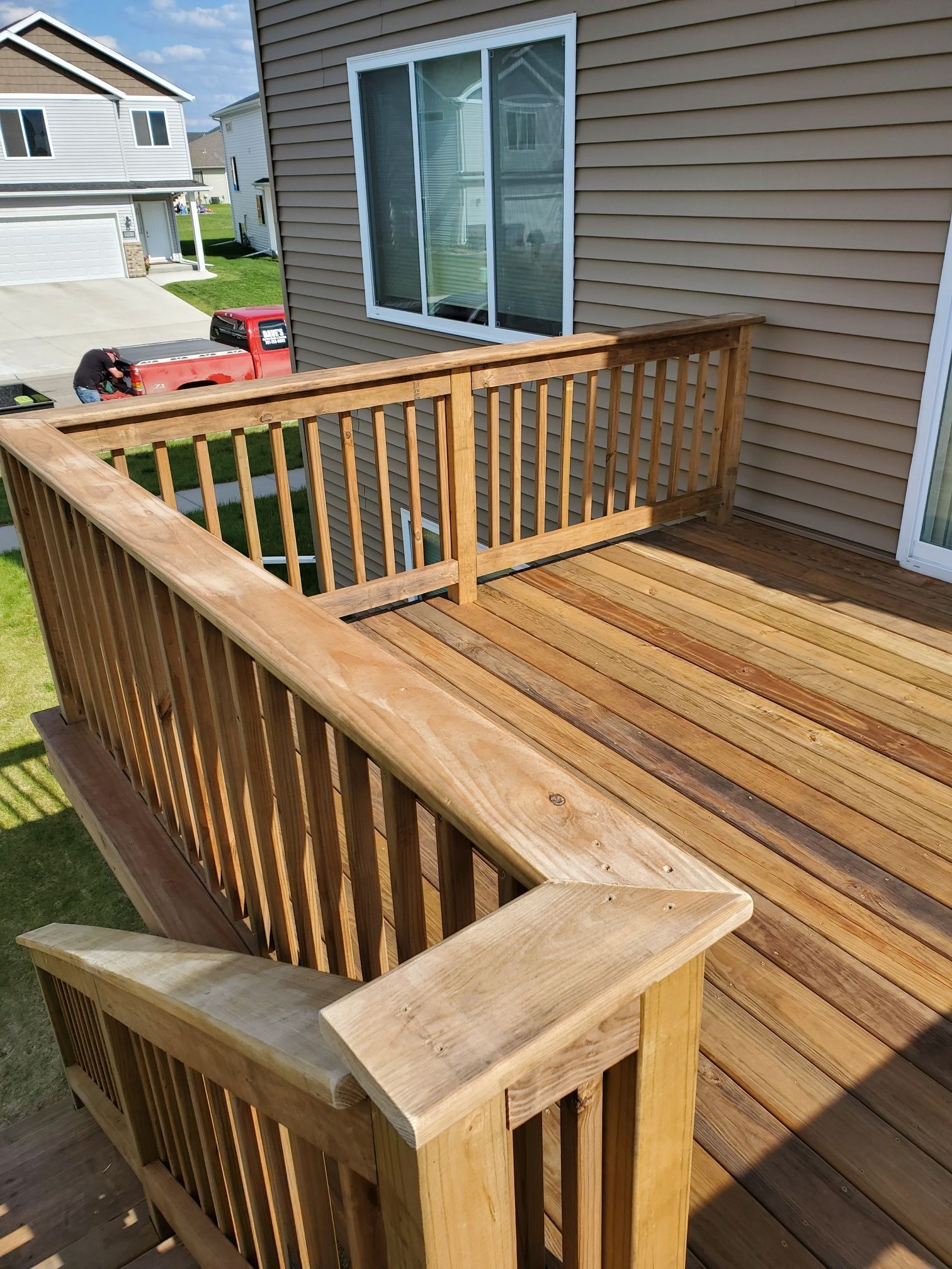 A wooden deck with stairs leading up to it is in front of a house.