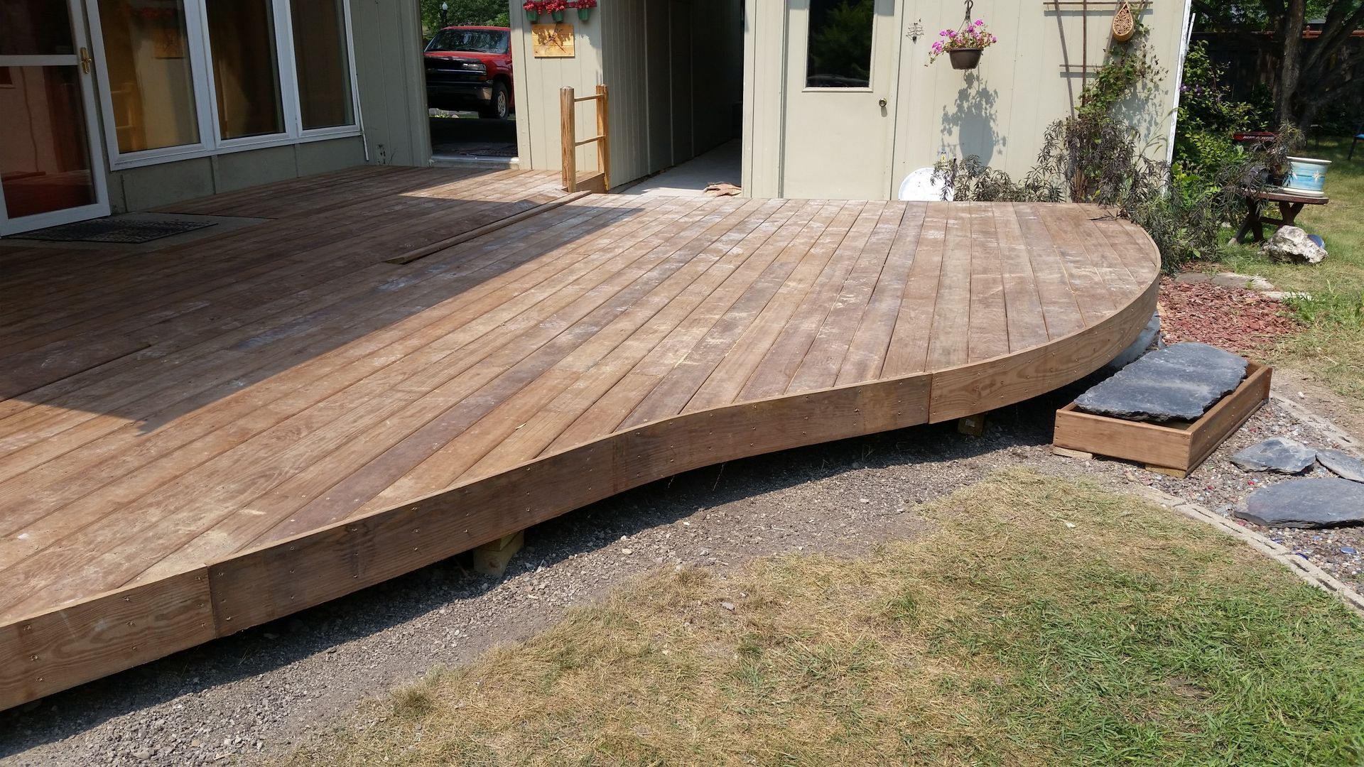 A wooden deck is sitting in the grass in front of a house.