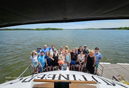 A group of people are posing for a picture on the back of a boat.