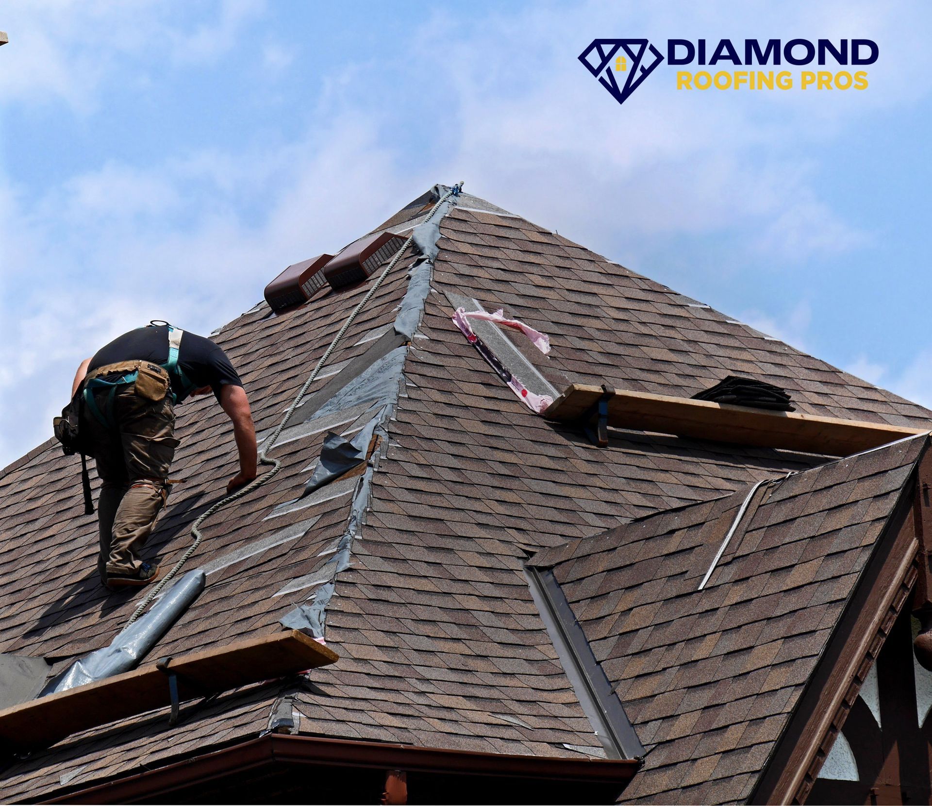 Roofers repairing a steep shingled roof under a blue sky, with Diamond Roofing Pros logo