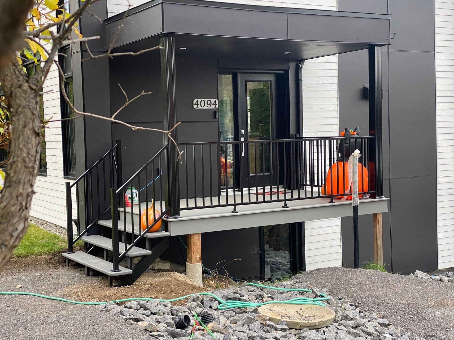 Porche et entrée modernes noirs avec escalier, rampe et cônes de signalisation orange à côté d'un bâtiment