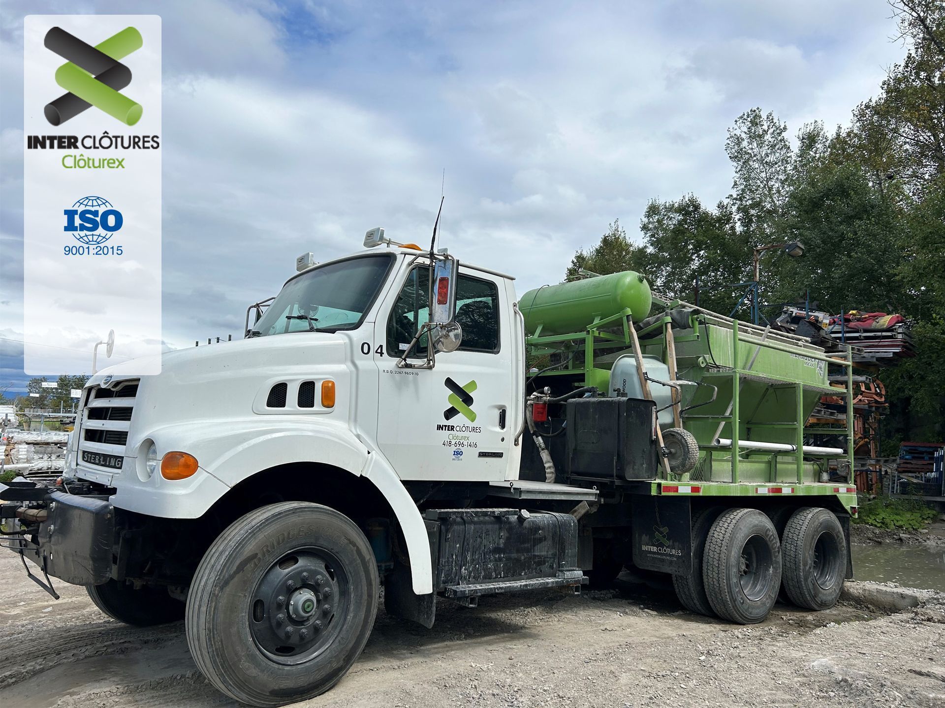 Camionnette utilitaire blanche avec équipement vert monté à l'arrière, garée à l'extérieur sous un ciel nuageux
