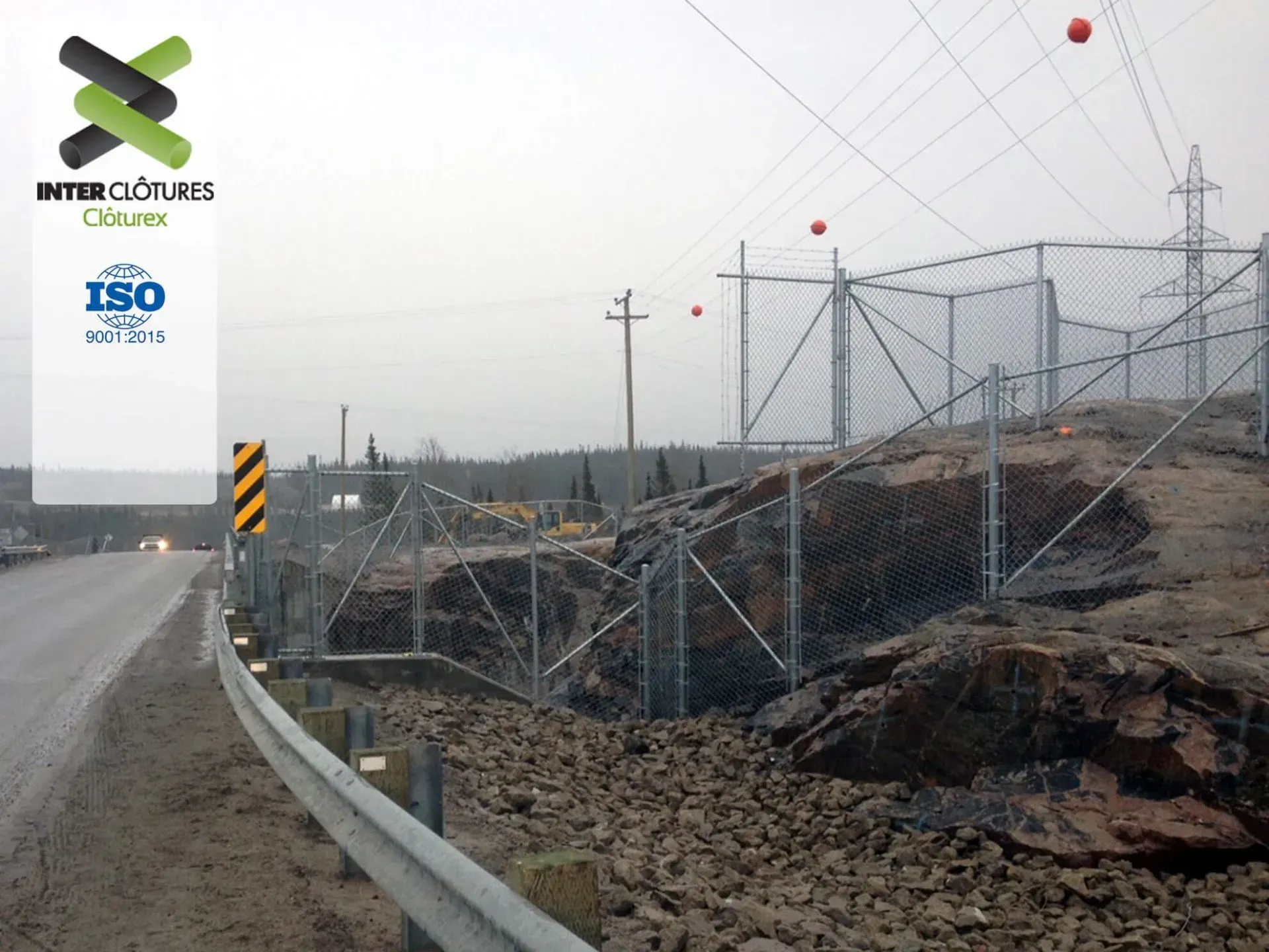 Garde-fous endommagés en bordure de route et gravats à côté d'un chantier clôturé sous un ciel gris