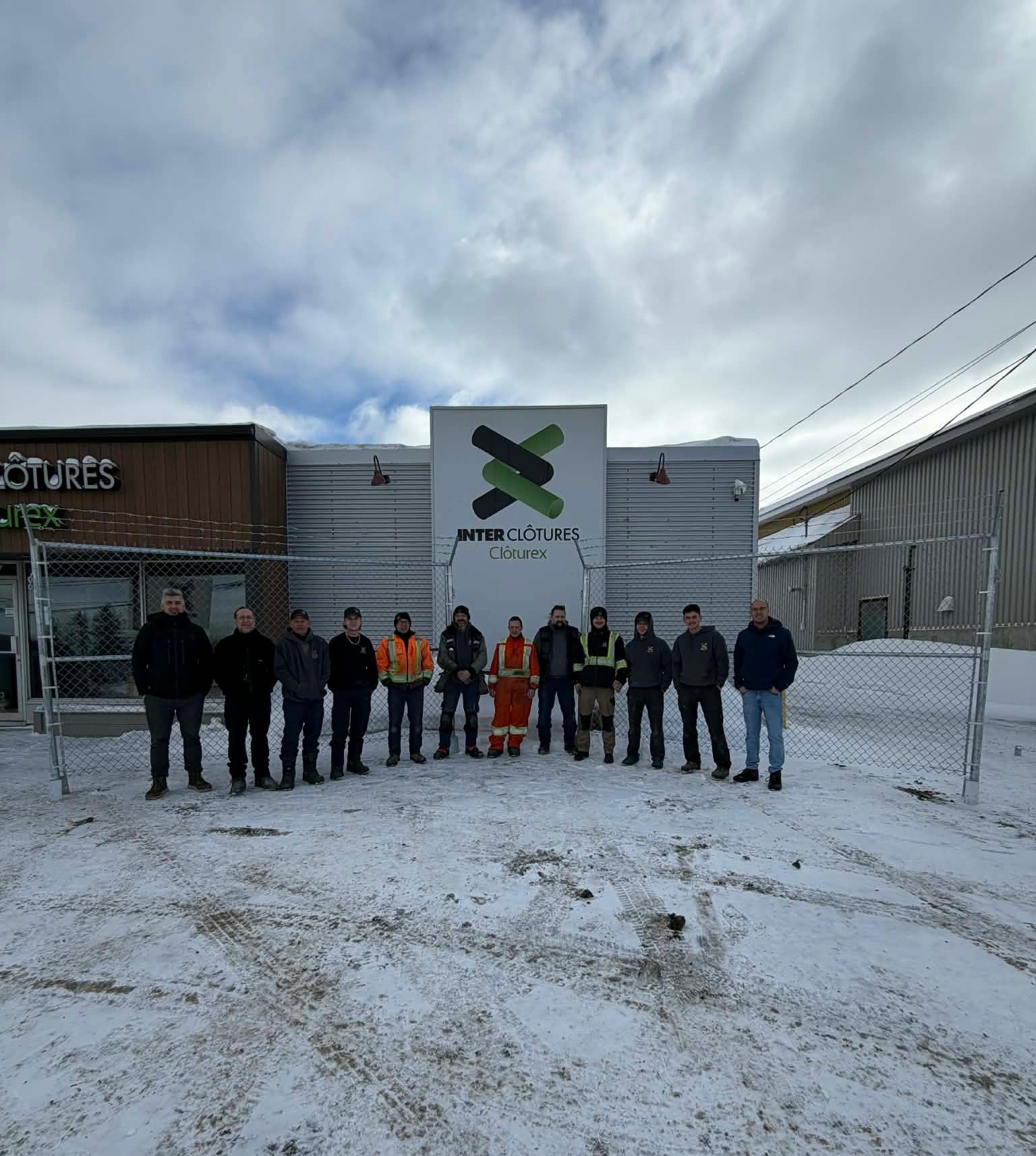 Groupe de personnes debout dans la neige devant un bâtiment sous un ciel nuageux