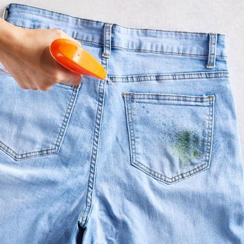 A person is spraying a pair of jeans with a spray bottle