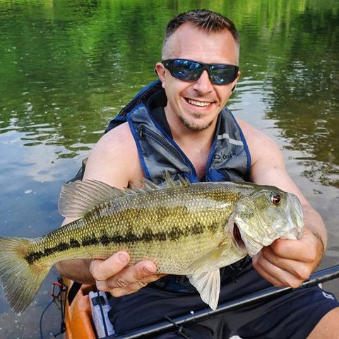 a man in a kayak is holding a large fish in his hands .